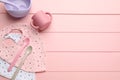 Flat lay composition with drool baby bibs and plastic dishware on pink wooden background. Space for text