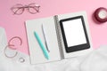 Flat lay composition with e-book reader, notebook and glasses on pink background. Space for text Royalty Free Stock Photo