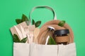 Flat lay composition with eco friendly dishware in bag on green background, top view