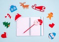 Flat lay composition with empty open notebook pen with Santa Claus and Christmas toys on blue background