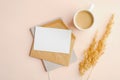 Flat lay composition with envelope, invitation card mockup, cup of coffee and dry flowers on beige background. Top view wedding