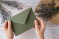 Flat lay composition of female hands holding green envelope with dry lavender flowers. Copy space template mock up. Top Royalty Free Stock Photo