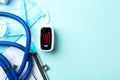 Flat lay composition with fingertip pulse oximeter and medical items on light blue background. Space for text Royalty Free Stock Photo