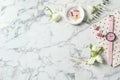 Flat lay with flowers, notebook and wristwatch on white marble background, space for text