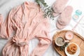 Flat lay composition with fluffy slippers and bath robe on white bedsheet. Comfortable home outfit