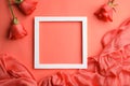 Flat lay composition with frame, roses and fabric on coral background.