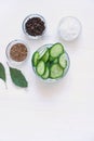 Flat lay of cucumber sliced in a glass bowl and spices for picklingfermenting- dill seeds, pepper, salt on a white wooden table.