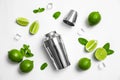 Flat lay composition with fresh juicy limes, mint, ice cubes and cocktail shaker on white background