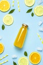 Flat lay composition with glass bottles of juice or fresh, slices of fresh lemon and orange, green leaves, ice cubes on blue Royalty Free Stock Photo