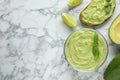 Flat lay composition with guacamole, sandwich and avocados on white marble table