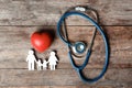 Flat lay composition with heart, stethoscope and family figure on wooden background. Royalty Free Stock Photo