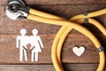 Flat lay composition with heart, stethoscope and paper silhouette of family on wooden background. Royalty Free Stock Photo
