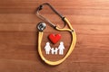 Flat lay composition with heart, stethoscope and paper silhouette of family on wooden background. Royalty Free Stock Photo