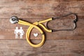 Flat lay composition with heart, stethoscope and paper silhouette of family on wooden background. Life insurance