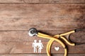 Flat lay composition with heart, stethoscope and paper silhouette of family on wooden background, space for text. Royalty Free Stock Photo