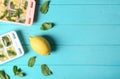 Flat lay composition with ice cube tray, mint and lemon on wooden background.