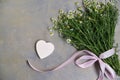 Flat-lay composition, including small camomiles bouquet tied with pink ribbon and cardboard heart-shaped figurines on grey wooden Royalty Free Stock Photo