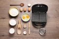 Flat lay composition with ingredients and Belgian waffle maker on table