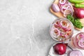 Flat lay composition with jars of pickled onions on marble table.