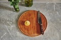 Top view of a knife and cut lemon in half on round wooden kitchen board near a glass with mint on a kitchen countertop Royalty Free Stock Photo