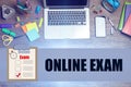 Flat lay composition with laptop, smartphone and phrase ONLINE EXAM on background