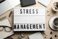 Flat lay composition of lightbox with phrase Stress Management on wooden table