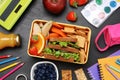 Flat lay composition with lunch box, tasty healthy food and school stationery on grey table Royalty Free Stock Photo