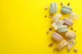 Flat lay composition with macarons, white bellflowers and pistachios on yellow background. Space for text