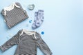 Flat lay composition with marine style baby clothes kit on pastel blue background. Striped kids bodysuit, shirst, socks