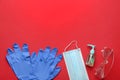 Flat lay composition with medical gloves, mask and hand sanitizer on red background. Space for text Royalty Free Stock Photo