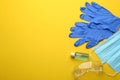 Flat lay composition with medical gloves, masks and hand sanitizer on yellow background. Space for text Royalty Free Stock Photo