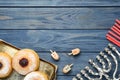 Flat lay composition of menorah, red candles, dreidels with He, Pe, Nun, Gimel letters and sufganiyot on blue wooden table, space Royalty Free Stock Photo