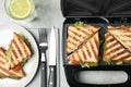 Flat lay composition with modern sandwich maker and breakfast served on grey table Royalty Free Stock Photo