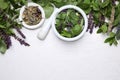 Flat lay composition with mortar and healing herbs on white wooden table, space for text