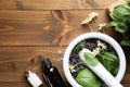 Flat lay composition with mortar and healing herbs on wooden table, space for text