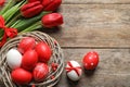 Flat lay composition of nest with painted Easter eggs and flowers on wooden table Royalty Free Stock Photo