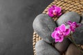 Flat lay composition with orchid  and spa stones on grey table. Space for text Royalty Free Stock Photo