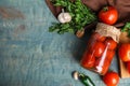 Flat lay composition with pickled tomatoes in glass jar on blue wooden table