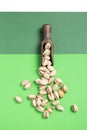 Flat lay composition. Pistachios on wooden spoon on green background. vertical format