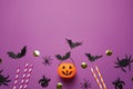 Flat lay composition with plastic pumpkin basket and paper bats on purple background, space for text. Halloween celebration Royalty Free Stock Photo