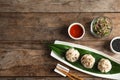 Flat lay composition with plate of tasty baozi dumplings, sesame seeds, sprouts and sauce on wooden table