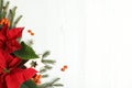 Flat lay composition with poinsettias traditional Christmas flowers and fir branches on white wooden table. Space for text