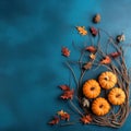 Flat lay composition of pumpkins, fall leaves, dry twigs on blue textured background.