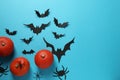 Flat lay composition with pumpkins, paper bats and spiders on light blue background, space for text. Halloween celebration Royalty Free Stock Photo