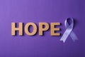 Flat lay composition with purple ribbon and word HOPE on violet background Royalty Free Stock Photo