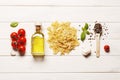 Flat lay composition of raw pasta, spices, cherry tomatoes, basil, butter with place for text. Royalty Free Stock Photo