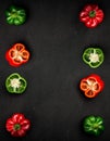 Flat lay composition with red and green paprika peppers whole and half on black background