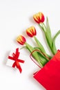 Flat lay composition with red yellow tulips in a red paper bag with gift on a white background. Valentin Day, Birthday, Mother day Royalty Free Stock Photo