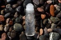 Flat lay composition of a roll on transparent deodorant bottle on wet beach stones Royalty Free Stock Photo