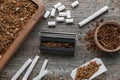 Flat lay composition with roller and tobacco on old wooden table. Making hand rolled cigarettes Royalty Free Stock Photo